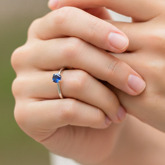 Mano de modelo usando un anillo solitario en oro blanco de 18 quilates con cristal azul de Joyería Caracas. 
