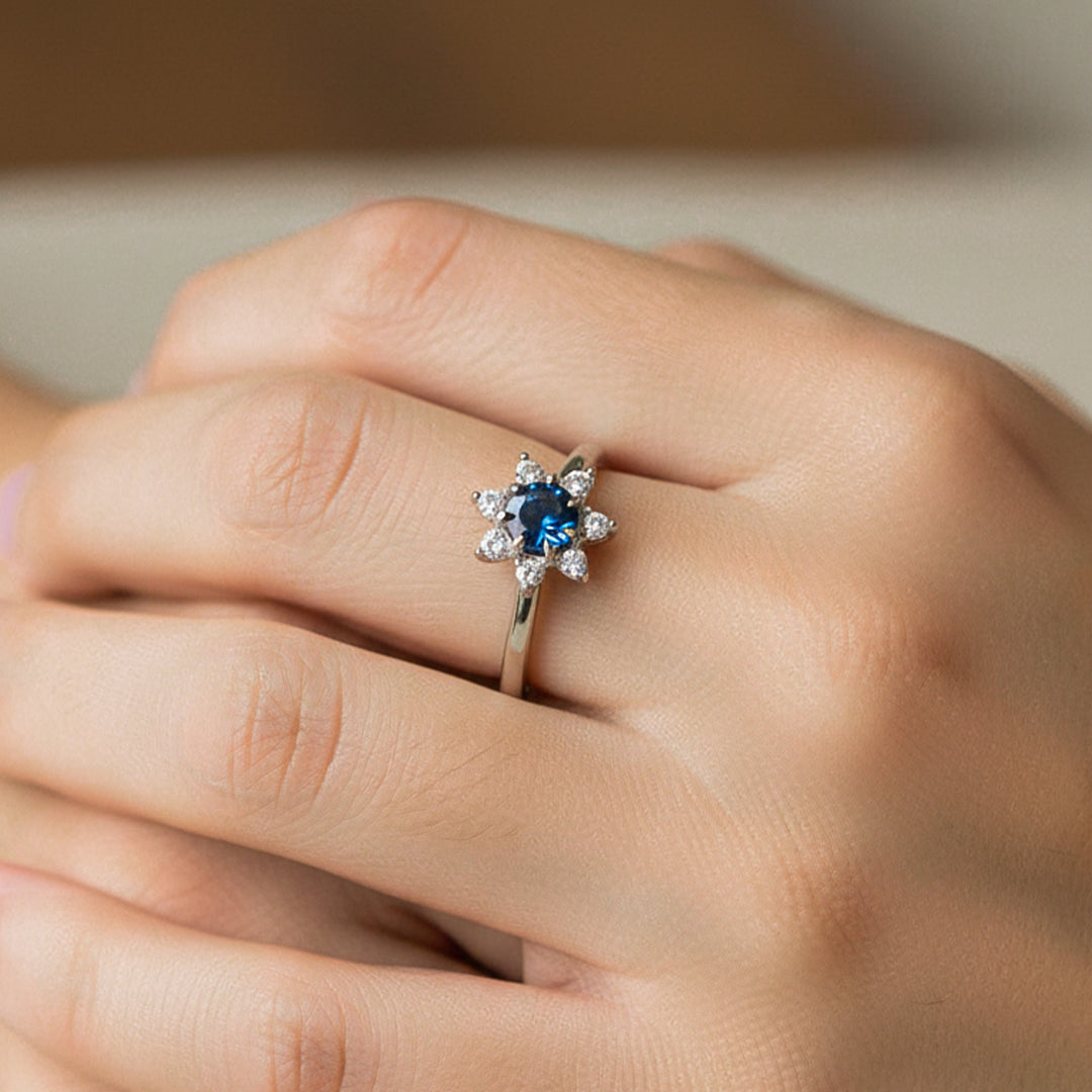 Mano de modelo usando un anillo con forma de flor en oro blanco de 18 quilates con Zafiro y Diamantes de Joyería Caracas. 