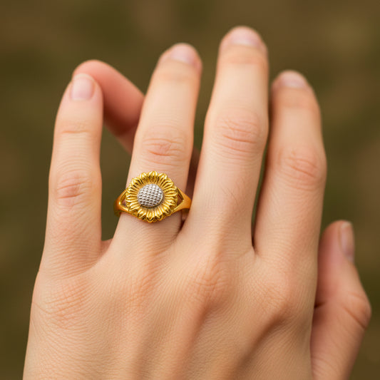 Mano de mujer usando un anillo con la forma de un girasol en el centro en oro amarillo y blanco de 18 quilates de Joyería Caracas. 