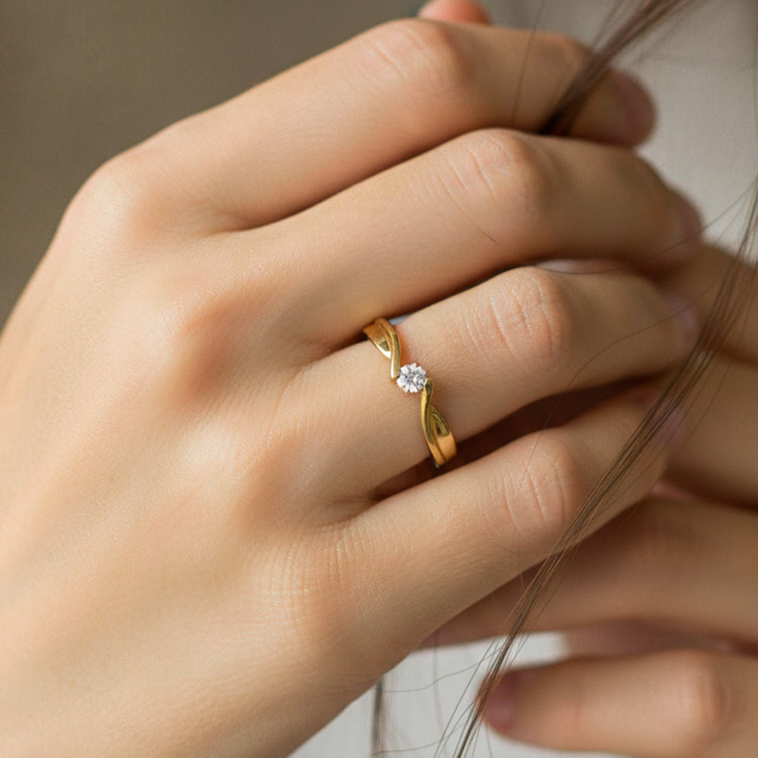 Mano de modelo usando un anillo solitario con diseño de onda y cristal en el centro de Joyería Caracas. 