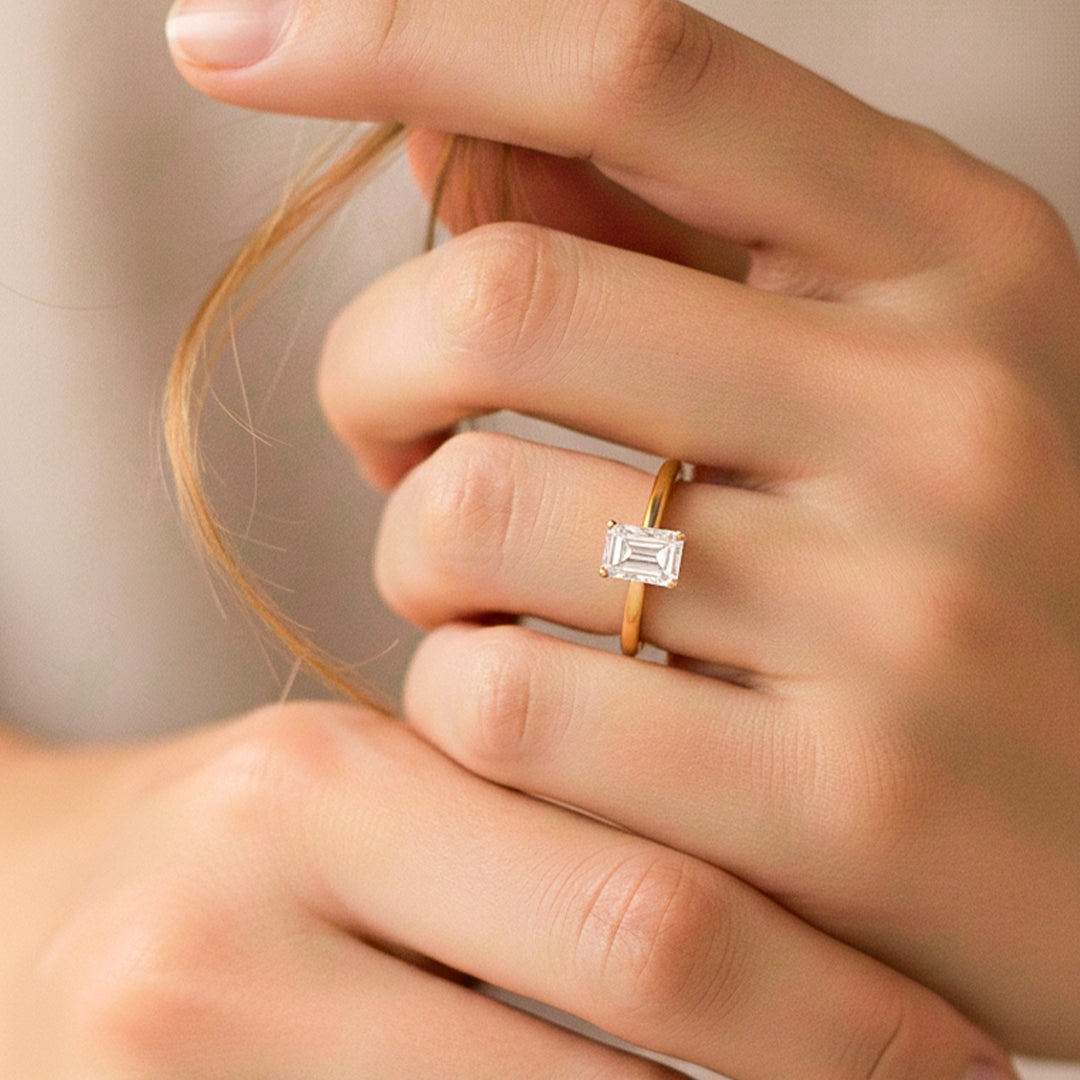 Mano de modelo usando un anillo en oro amarillo de 18 quilates con cristal en corte de baguette de Joyería Caracas. 