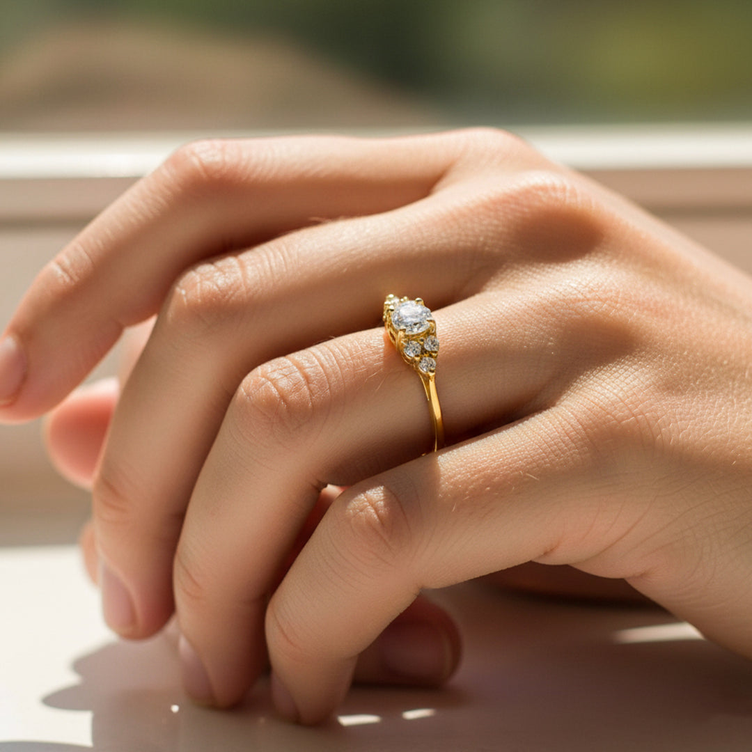 Mano de mujer usando un anillo en oro amarillo de 18 quilates con cristales de color blanco de Joyería Caracas. 