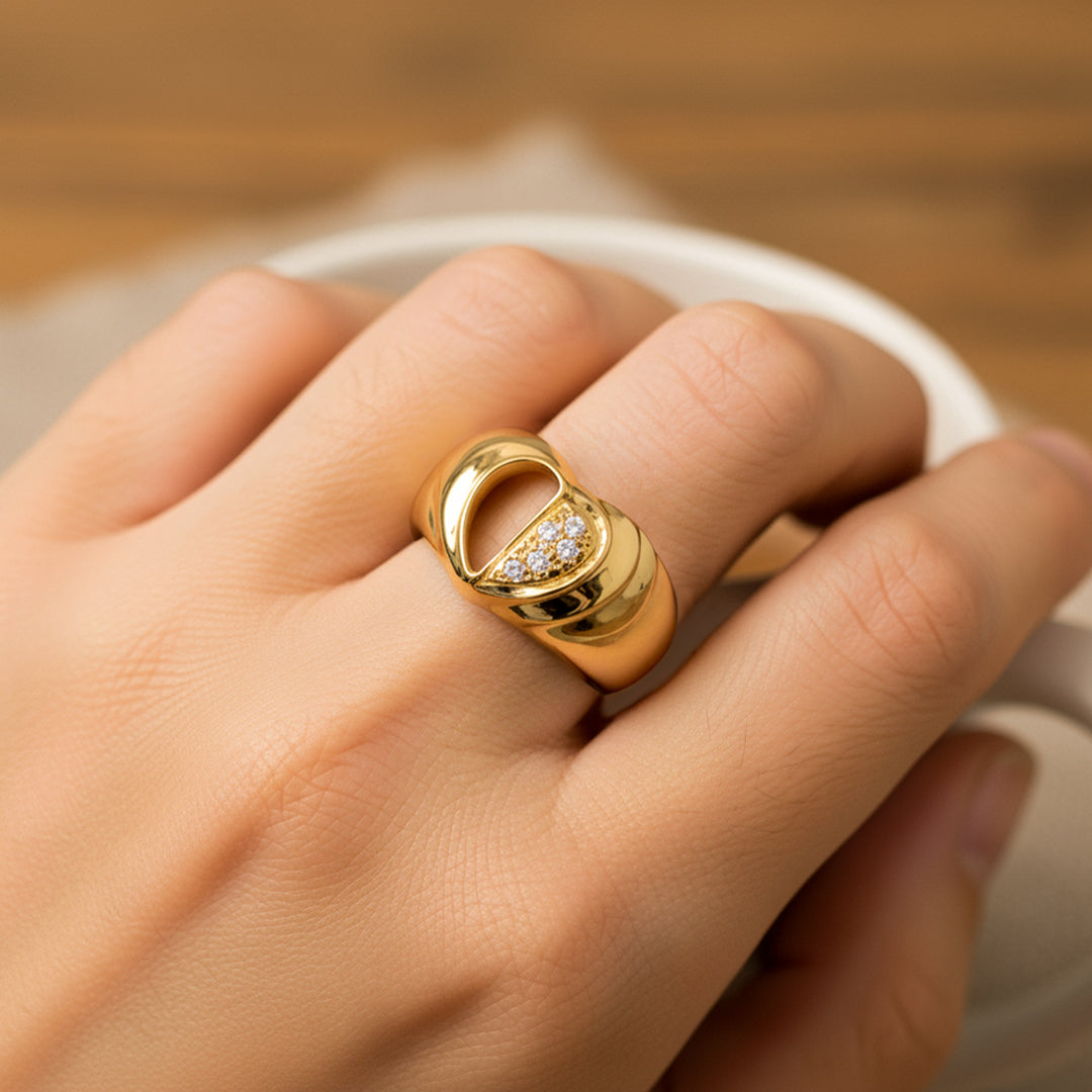 Mano de mujer usando un anillo con la forma de medio corazón en oro amarillo de 18 quilates con cristales de color blanco de Joyería Caracas. 