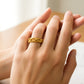 Mano de mujer usando un anillo con forma de lazos entorchados en oro amarillo de 18 quilates de Joyería Caracas. 