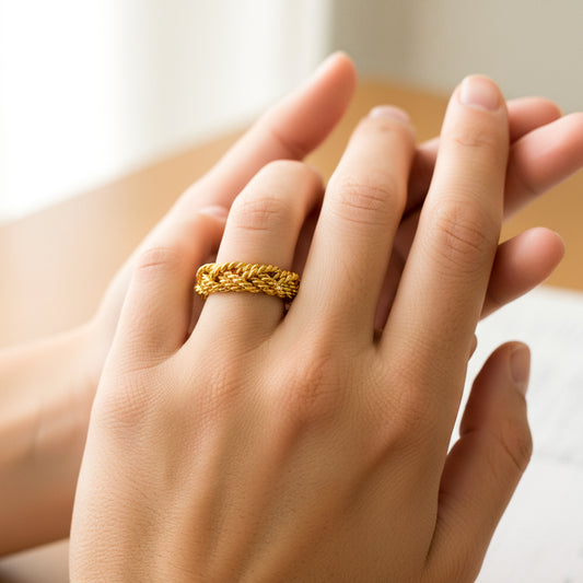 Mano de mujer usando un anillo con forma de lazos entorchados en oro amarillo de 18 quilates de Joyería Caracas. 
