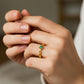 Mano de mujer usando un anillo con infinitos en oro amarillo de 18 quilates con Esmeralda en el centro de Joyería Caracas. 
