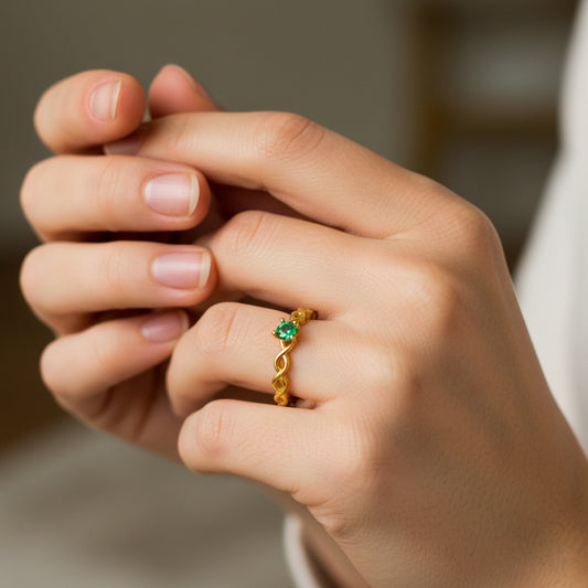 Mano de mujer usando un anillo con infinitos en oro amarillo de 18 quilates con Esmeralda en el centro de Joyería Caracas. 
