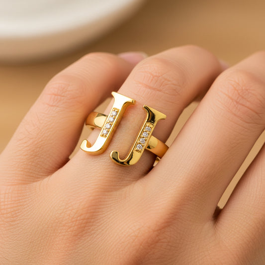 Mano de mujer usando un anillo con letras personalizadas en oro amarillo de 18 quilates de Joyería Caracas. 