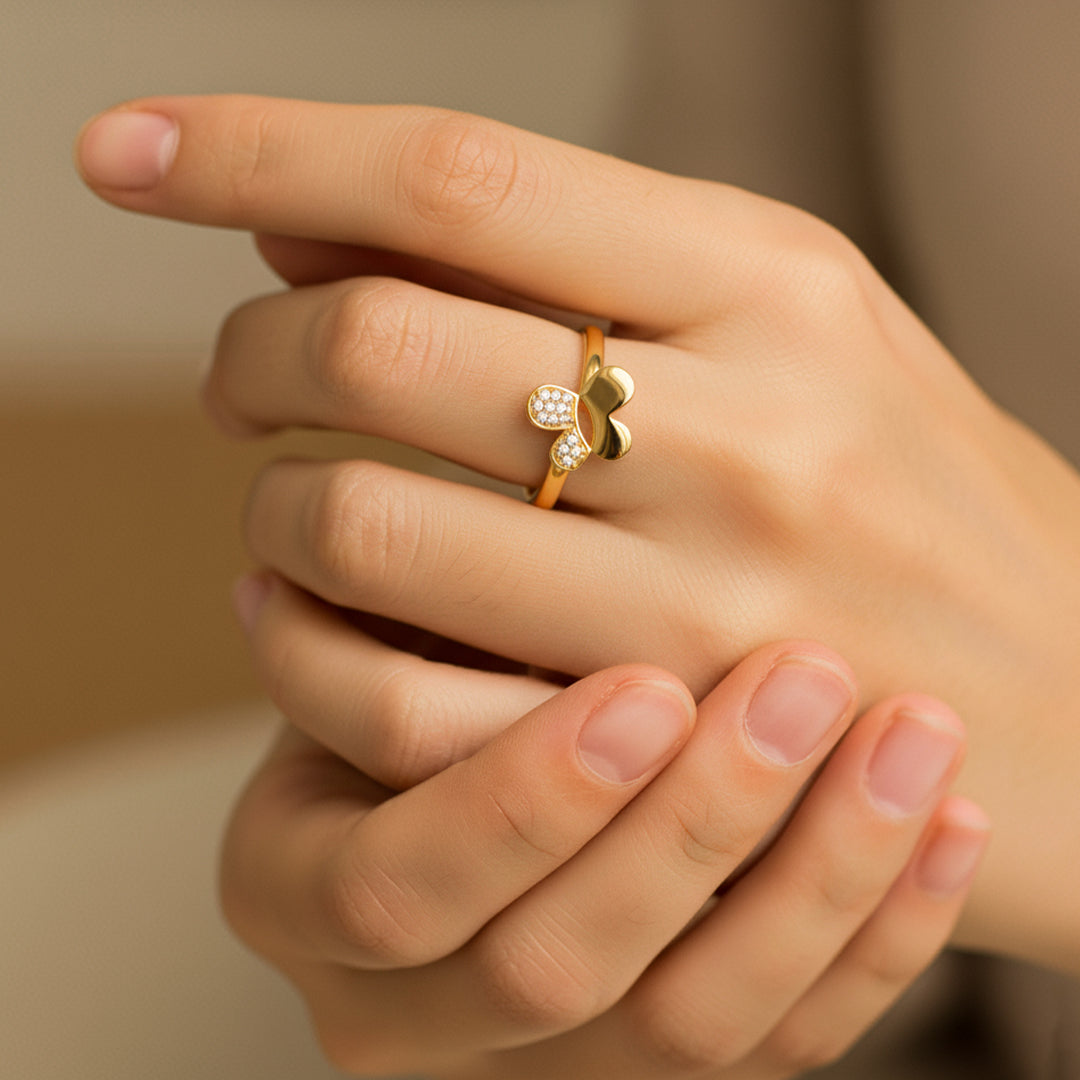 Mano de mujer usando un anillo con forma de mariposa en el centro en oro amarillo de 18 quilates con cristales de color blanco de Joyería Caracas. 