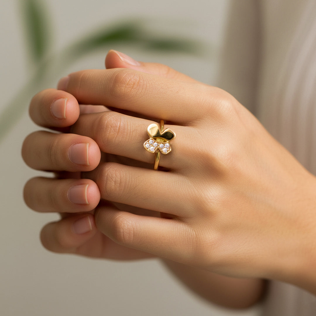 Mano de mujer usando un anillo con forma de mariposa en el centro en oro amarillo de 18 quilates con cristales de color blanco de Joyería Caracas. 