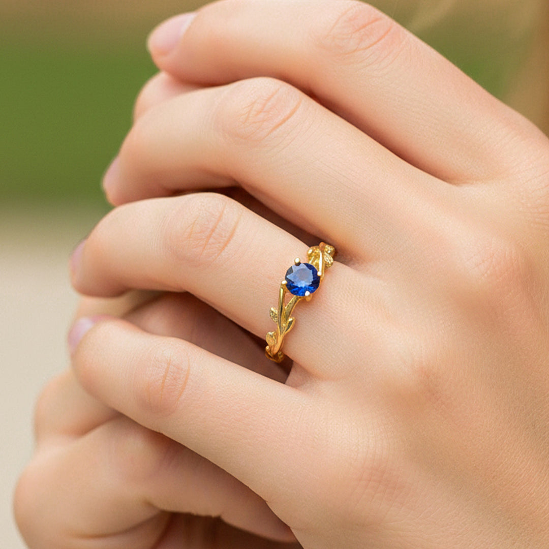 Mano de modelo usando un anillo con formas de ramas en oro amarillo de 18 quilates con Zafiro natural de Joyería Caracas. 