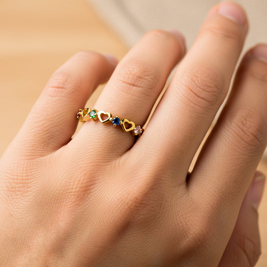 Mano de mujer usando un anillo con corazones en oro amarillo de 18 quilates y cristales de diferentes colores de Joyería Caracas. 