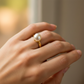 Mano de mujer usando un anillo en oro amarillo de 18 quilates con perla redonda natural de Joyería Caracas. 