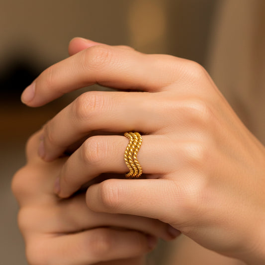 Mano de mujer usando un anillo de ondas entorchadas en oro amarillo de 18 quilates de Joyería Caracas. 