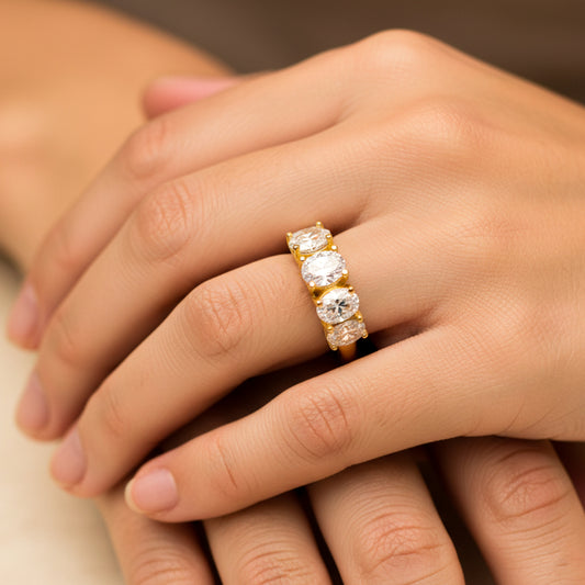 Mano de mujer usando un anillo en oro amarillo de 18 quilates con cristales ovalados de color blanco de Joyería Caracas. 