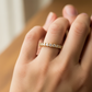 Mano de mujer usando un anillo pisargolla en oro amarillo de 18 quilates con cristales de color blanco de Joyería Caracas. 