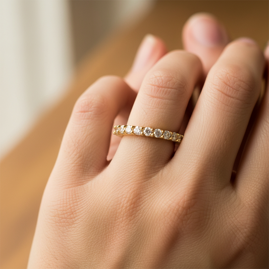 Mano de mujer usando un anillo pisargolla en oro amarillo de 18 quilates con cristales de color blanco de Joyería Caracas. 