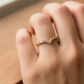 Mano de mujer usando un anillo pisargolla con forma de punta en el centro en oro amarillo de 18 quilates con cristales de color blanco de Joyería Caracas. 