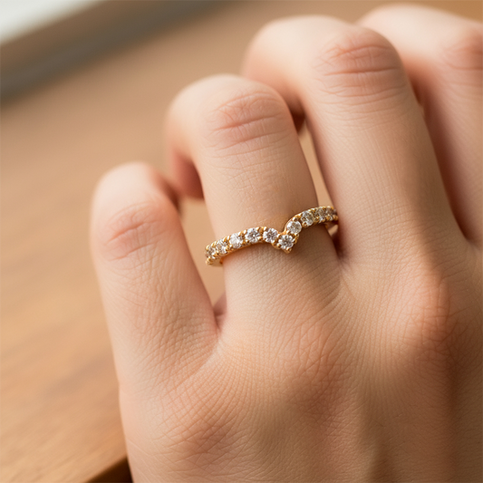 Mano de mujer usando un anillo pisargolla con forma de punta en el centro en oro amarillo de 18 quilates con cristales de color blanco de Joyería Caracas. 