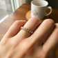 Mano de mujer usando un anillo pisargolla en oro amarillo de 18 quilates con cristales de color blanco de Joyería Caracas. 