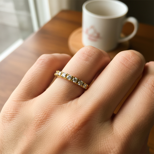 Mano de mujer usando un anillo pisargolla en oro amarillo de 18 quilates con cristales de color blanco de Joyería Caracas. 