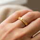Mano de mujer usando un anillo pisargolla en oro amarillo de 18 quilates con cristales de color blanco de Joyería Caracas. 