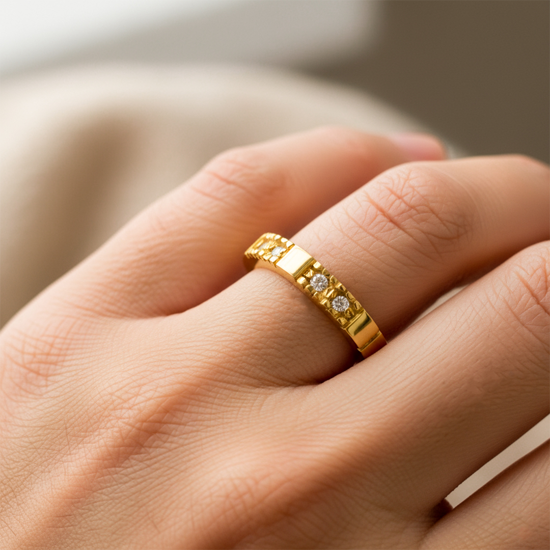 Mano de mujer usando un anillo pisargolla en oro amarillo de 18 quilates con cristales de color blanco de Joyería Caracas. 