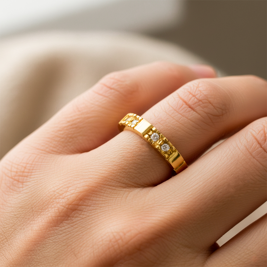 Mano de mujer usando un anillo pisargolla en oro amarillo de 18 quilates con cristales de color blanco de Joyería Caracas. 