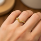 Mano de mujer usando un anillo pisargolla en oro amarillo de 18 quilates con una forma circular en la parte de abajo con cristales de color blanco de Joyería Caracas. 