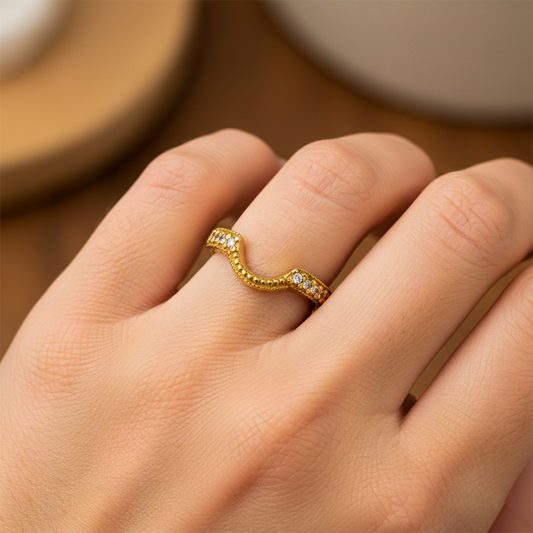 Mano de mujer usando un anillo pisargolla en oro amarillo de 18 quilates con una forma circular en la parte de abajo con cristales de color blanco de Joyería Caracas. 