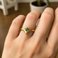 Mano de mujer usando un anillo en oro amarillo de 18 quilates con forma en punta con cristal de color verde de Joyería Caracas. 