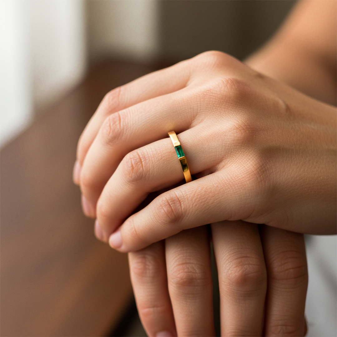 Mano de mujer usando un anillo en oro amarillo de 18 quilates con Esmeralda en el centro en forma rectangular de Joyería Caracas. 