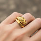 Mano de mujer usando un anillo con forma de serpiente clásica en oro amarillo de 18 quilates con cristales de color negro y rojo de Joyería Caracas. 