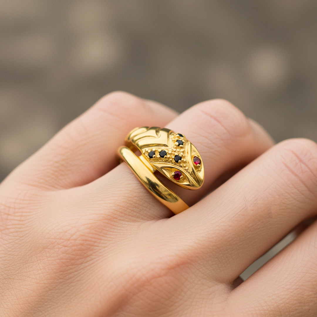 Mano de mujer usando un anillo con forma de serpiente clásica en oro amarillo de 18 quilates con cristales de color negro y rojo de Joyería Caracas. 