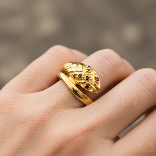 Mano de mujer usando un anillo con forma de serpiente clásica en oro amarillo de 18 quilates con cristales de color negro y rojo de Joyería Caracas. 