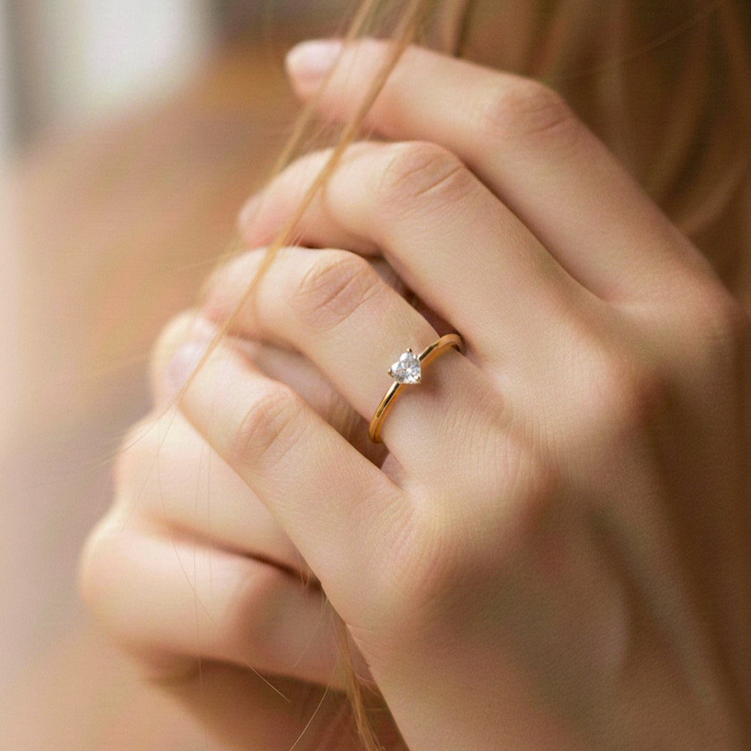Mano de modelo usando un anillo en oro amarillo de 18 quilates con cristal en forma de corazón de Joyería Caracas. 
