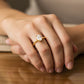 Mano de mujer usando un anillo en oro amarillo de 18 quilates con cristal ovalado de color blanco de Joyería Caracas. 