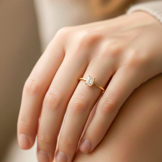 Mano de modelo usando un anillo en oro amarillo de 18 quilates con cristal en corte baguette de Joyería Caracas. 