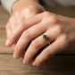 Mano de mujer usando un anillo en oro amarillo de 18 quilates con cristal redondo de color verde de Joyería Caracas. 