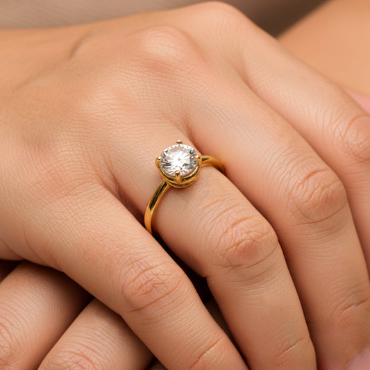 Mano de mujer usando un anillo en oro amarillo de 18 quilates con cristal redondo en el centro de Joyería Caracas. 