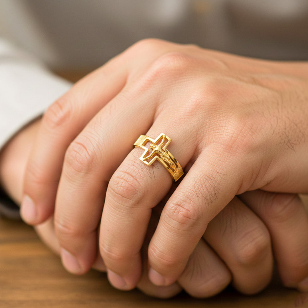 Mano de hombre usando un anillo con la silueta de cruz y Cristo en oro amarillo de 18 quilates de Joyería Caracas. 