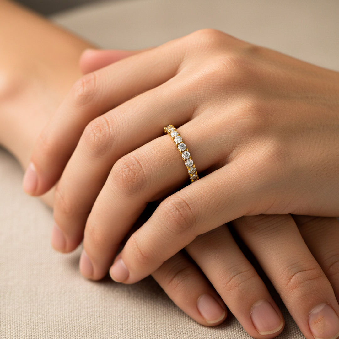 Mano de mujer usando un anillo sin fin en oro amarillo de 18 quilates con cristales de color blanco alrededor de Joyería Caracas. 