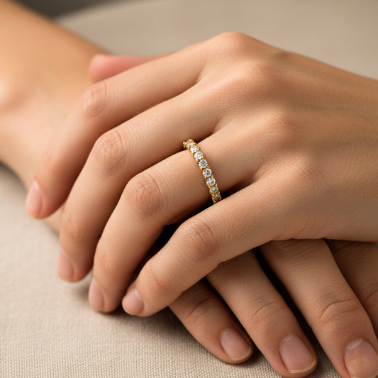 Mano de mujer usando un anillo sin fin en oro amarillo de 18 quilates con cristales de color blanco alrededor de Joyería Caracas. 