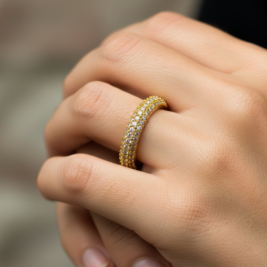 Mano de mujer usando un anillo en oro amarillo de 18 quilates con cristales de color blanco de Joyería Caracas. 