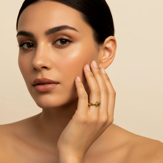 Mano de mujer usando un anillo en oro amarillo de 18 quilates con estrella en el centro y cristal de color verde de Joyería Caracas. 