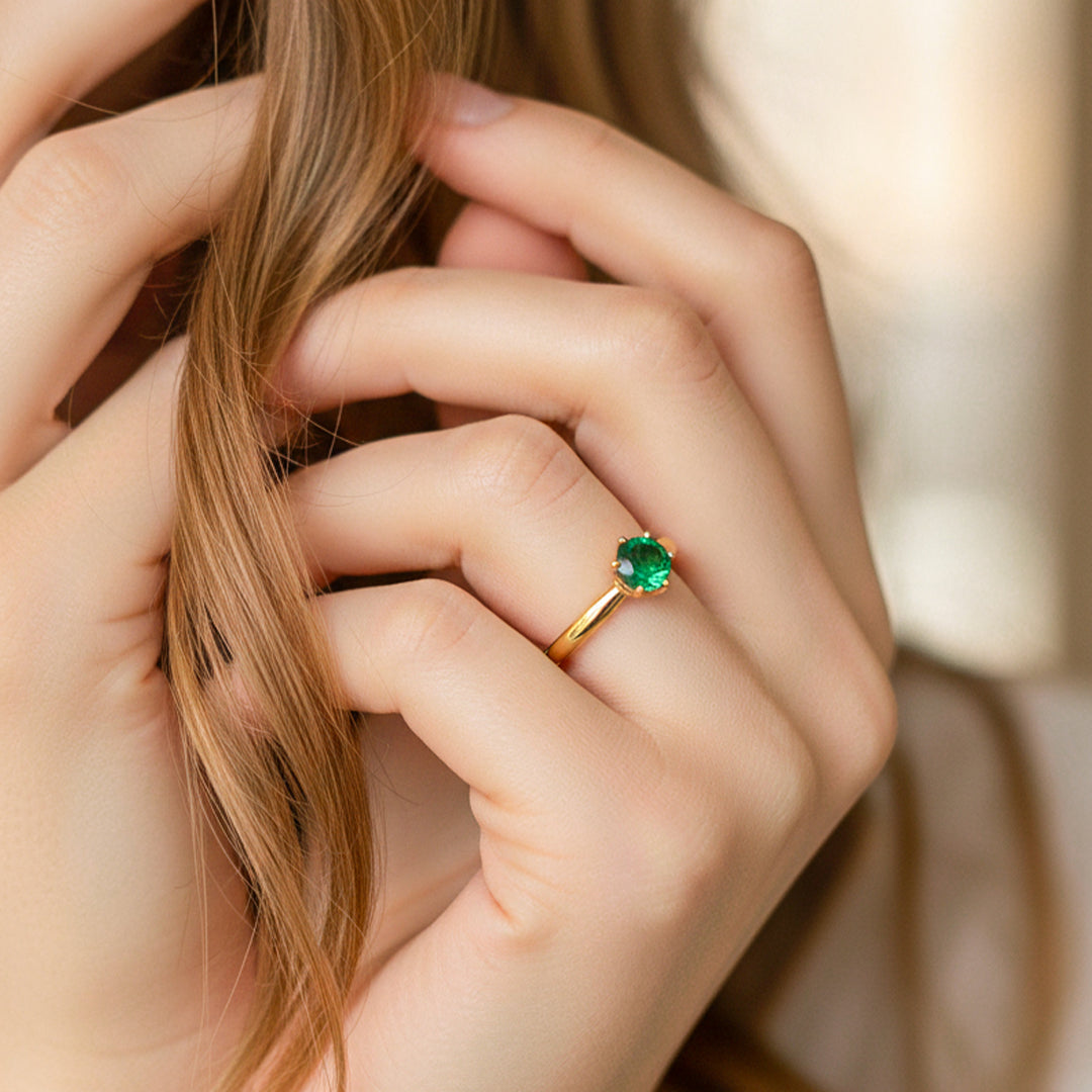Mano de modelo usando un anillo solitario en oro amarillo de 18 quilates con cristal verde de Joyería Caracas.