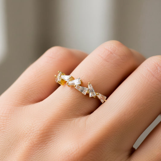 Mano de mujer usando un anillo en oro amarillo de 18 quilates con cristales en forma de trapecios de color blanco de Joyería Caracas. 