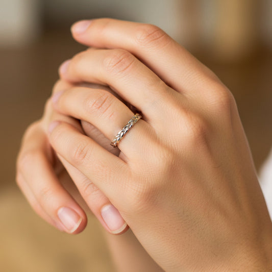 Mano de mujer usando un anillo trenzado en oro blanco de 18 quilates de Joyería Caracas. 