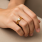 Mano de mujer usando un anillo con formas de triángulos en oro amarillo de 18 quilates con un cristal triangular de color blanco en el centro de Joyería Caracas. 