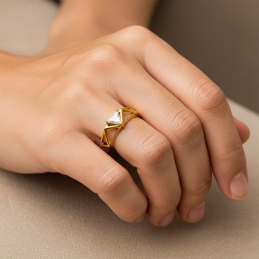 Mano de mujer usando un anillo con formas de triángulos en oro amarillo de 18 quilates con un cristal triangular de color blanco en el centro de Joyería Caracas. 